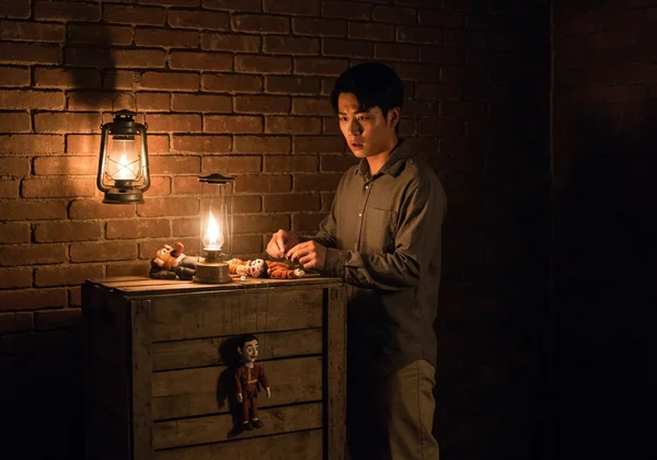 A figure subtly manipulating strings behind a curtain